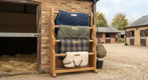 A neat display rack featuring various sizes and weights of pony stable rugs in a traditional British equestrian yard.