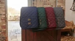 A range of different coloured heavyweight stable rugs displayed on a wooden stable door